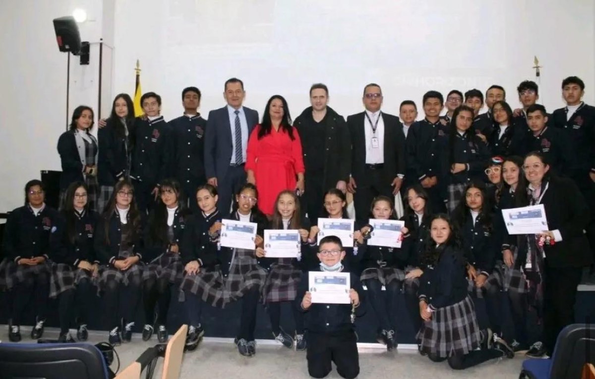 Grupo grande de estudiantes con diplomas en escenario