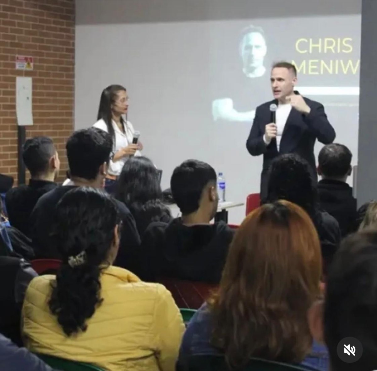 Chris Meniw dando una charla a jóvenes en auditorio universitario